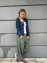Chaqueta azul marino de estilo militar, con cuello mao, detalles de cintas satinadas y botones metálicos dorados en el frente y en los puños.