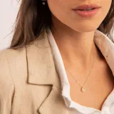Conjunto compuesto por cadena fina y dije circular con circonia central engastada en oro 18k.