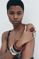 Pack de tres pulseras rígidas para mujer, una dorada metálica en relieve y dos de resina en color borgoña y negro con rayas blancas.