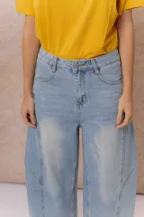 Pantalón de jean estilo barrel con tiro alto y pierna amplia de diseño curvo. Presenta un lavado celeste claro con efecto desgastado, cierre y botón frontal, y bolsillos funcionales.