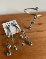Brazalete abierto de metal dorado con acabado martillado, decorado con piedras naturales en tono turquesa con incrustaciones doradas en los extremos.