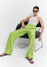 Pantalon wideleg de tiro medio en color verde lima, confeccionado en tejido fluido con pinzas frontales, bolsillos laterales, trabillas para cinturon y cierre oculto de boton, gancho y cremallera.