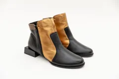 Botín de cuero negro con apliques dorados, punta almendrada, cierre lateral y taco cuadrado.