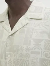 Camisa de manga corta con cuello resort y corte amplio. Confeccionada en tejido plano con estampado geométrico y botánico en tonos neutros.