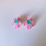 Aros tipo botón con forma de flor de pétalos turquesa y centro rosa y naranja.