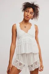 Conjunto de dos piezas color blanco, compuesto por una musculosa con escote en V con detalles de encaje y volados en el torso, y un short a juego con terminaciones de encaje calado en el ruedo.