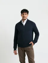 Cardigan de punto color marrón, con cuello alto y cierre frontal completo. Presenta mangas largas tipo ranglan y bolsillos laterales de ribete.