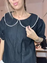 Blusa negra de lino con cuello Peter Pan blanco y mangas cortas abullonadas.