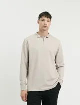 Remera de punto canalé francés, color beige, con cuello polo, manga larga y cierre frontal de metal.