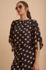 Blusa negra con estampado de estrellas color beige con contorno fucsia, mangas cortas amplias y escote redondo.