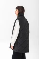 Chaleco acolchado de corte recto y largo medio, con diseño de rombos, cuello alto y cierre frontal con botones a presión.