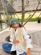 Gorra tipo polo con cuerpo de tela verde y visera de cuero marrón, con un caballo bordado en el frente.