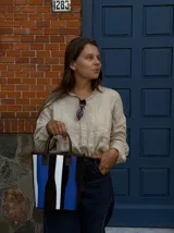 Matera de cuero con diseño de paneles verticales en combinación de colores azul, verde, marrón y bordó. Cuenta con dos asas cortas de cuero y estructura rígida.