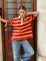 Remerón de algodón a rayas horizontales color naranja y salmón, con cuello tipo polo y mangas cortas.