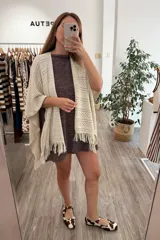 Ruana tejida color arena, con diseño calado de rombos y flecos en el borde inferior.