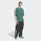 Remera Adidas de corte holgado en color verde, con cuello redondo, mangas cortas con las icónicas tres rayas blancas en los hombros y logo del trébol bordado en el pecho.
