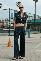 Chaleco de denim oscuro con cuello solapa, cierre frontal con cremallera metálica y bolsillos delanteros con tapeta. Presenta un diseño de corte abullonado con bajo elástico.