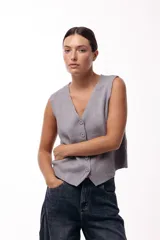 Chaleco tejido de punto con escote en V y cierre frontal con botones. Presenta una silueta recta y corte limpio, ideal para usar como prenda única o superpuesta.