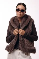 Chaleco acolchado color marrón con terminaciones de piel sintética en los bordes y cuello, aportando volumen y textura.