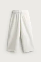 Pantalón relaxed fit de color blanco off-white, confeccionado en tejido con lino. Cuenta con pliegues frontales en la cintura, bolsillos delanteros y cierre frontal con cremallera y botón.