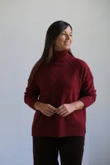 Polerón de cuello alto con diseño de rombos en relieve, mangas largas con puños acanalados y ruedo asimétrico con aberturas laterales.
