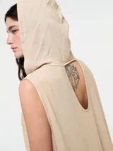 Vestido largo color beige, tipo túnica hoodie, de silueta amplia, con escote en V y capucha. Sin mangas.