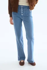 Jeans de tiro alto y corte acampanado, confeccionados en denim con leve elasticidad. Presentan cierre frontal con múltiples botones metálicos visibles, bolsillos de parche delanteros y diseño de perneras anchas desde la rodilla.