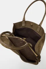 Bolso de hombro formato maxi city confeccionado en piel de gamuza color marrón. Cuenta con doble asa de hombro, doble compartimento interior y cierre mediante clip metálico y cremallera.