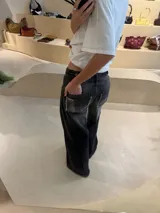 Pantalón de jean recto color gris oscuro, con efecto desgastado, recortes 360 y ajuste en cintura con presillas. Tiene tiro medio y detalles de bolsillos traseros con parches deshilachados.