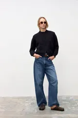 Cardigan negro de tejido de punto con sutiles destellos brillantes, cuello redondo, cierre frontal con botones y mangas largas con puños acanalados.