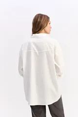 Camisa de algodón color blanco, de corte relajado y estilo western. Presenta detalle de tachas metálicas en la parte superior delantera y mangas largas con puños.