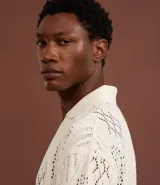 Camisa polo de mangas cortas color crema, confeccionada en tejido de punto calado con cuello inglés.