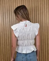Blusa sin mangas de diseño estructurado con múltiples líneas de frunces y elásticos horizontales, cuello alto con volado y diseño ajustado. Presenta estampado de rayas verticales.