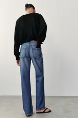 Jeans de tiro alto, pernera recta y larga, estilo clásico con cinco bolsillos, cierre frontal con cremallera y botón metálico.