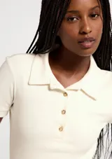 Remera polo de manga corta, color blanco, de corte ajustado con cuello camisero y cartera de tres botones frontales.