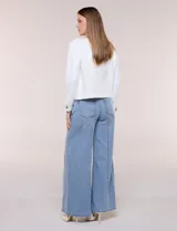 Camperita corta blanca de punto elastizado, con cuello camisero, cierre frontal completo y mangas largas con puños anchos abotonados.