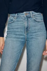 Jeans mom fit de tiro alto color negro con efecto lavado, diseño de cinco bolsillos y corte tobillero.