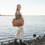 Bolso tipo tote bag color marrón camel, confeccionado en descarne vacuno gamuzado y cuero graneado. Tiene doble asa corta de hombro y correa larga extraíble. Presenta detalles fruncidos en los laterales, tres compartimentos interiores y dos bolsillos exteriores.