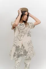 Vestido corto beige con estampado botánico en negro, cuello camisero, mangas cortas y cierre frontal con botones.