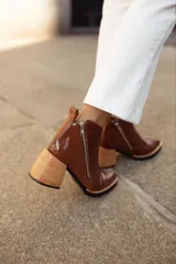 Botinetas de cuero con textura reptil en color bordó, con cierre lateral metálico y taco cuadrado de madera en tono natural.
