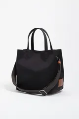 Bolso bandolera Bimba y Lola modelo Chihuahua de tamaño grande, color negro, con doble asa de mano y asa regulable de tejido. Cuenta con detalle de parche de cuero en un lateral, logo impreso en la parte inferior frontal y herrajes metálicos.