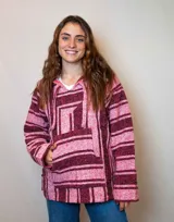 Buzo estilo mexicano con capucha, de tejido grueso a rayas horizontales en tonos rosa y borgoña.