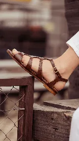 Sandalia plana tipo romana confeccionada 100% en cuero color negro, con múltiples tiras entrelazadas y cierre de hebilla lateral.