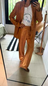 Pantalón sastrero de corte recto y tiro medio, confeccionado en tejido de lino con destellos de lurex, con cierre frontal y trabillas para cinturón.