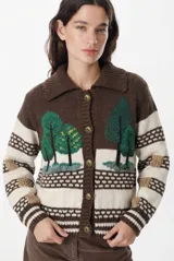 Cardigan de punto con diseño artesanal de paisaje boscoso, cuello polo y cierre frontal con botones metálicos. Presenta un patrón de franjas horizontales en tonos marrón, crema y detalles en beige, con mangas largas y puños acanalados.