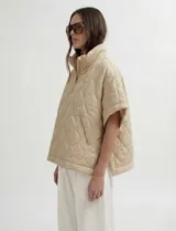 Poncho acolchado color vino tinto, con cuello alto y cierre frontal parcial. Presenta un patrón de costuras capitoné en forma de hoja o diamante y bolsillos delanteros.
