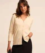 Cardigan de punto color beige, con escote en V, manga larga y cierre frontal mediante botones a tono. Diseño clásico y versátil.