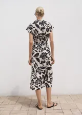 Vestido midi de viscosa con estampado floral en color crudo y negro, cuello camisero, manga corta, cierre frontal con botones y cinturón ajustable del mismo tejido.