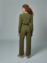 Mono enterito verde militar de lino, con solapas en el cuello, mangas largas y cinturón con hebilla forrada del mismo tono.
