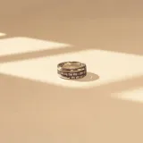 Anillo de diseño triple banda, elaborado en plata y oro, con una banda central decorada con circonias engastadas.